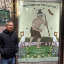 Marcelo Potosi stands on Market Street next to his Revitalizing the Culture poster for the series titled The Future of the Ramaytush Ohlone