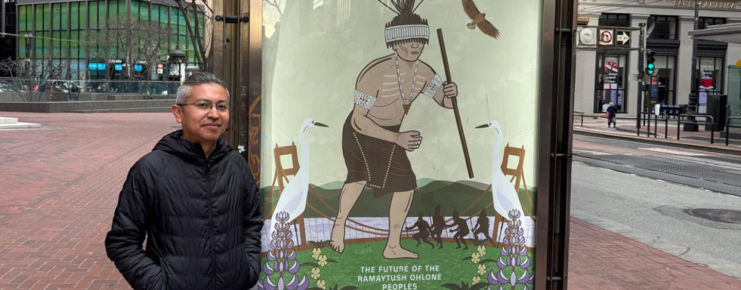 Marcelo Potosi stands on Market Street next to his Revitalizing the Culture poster for the series titled The Future of the Ramaytush Ohlone